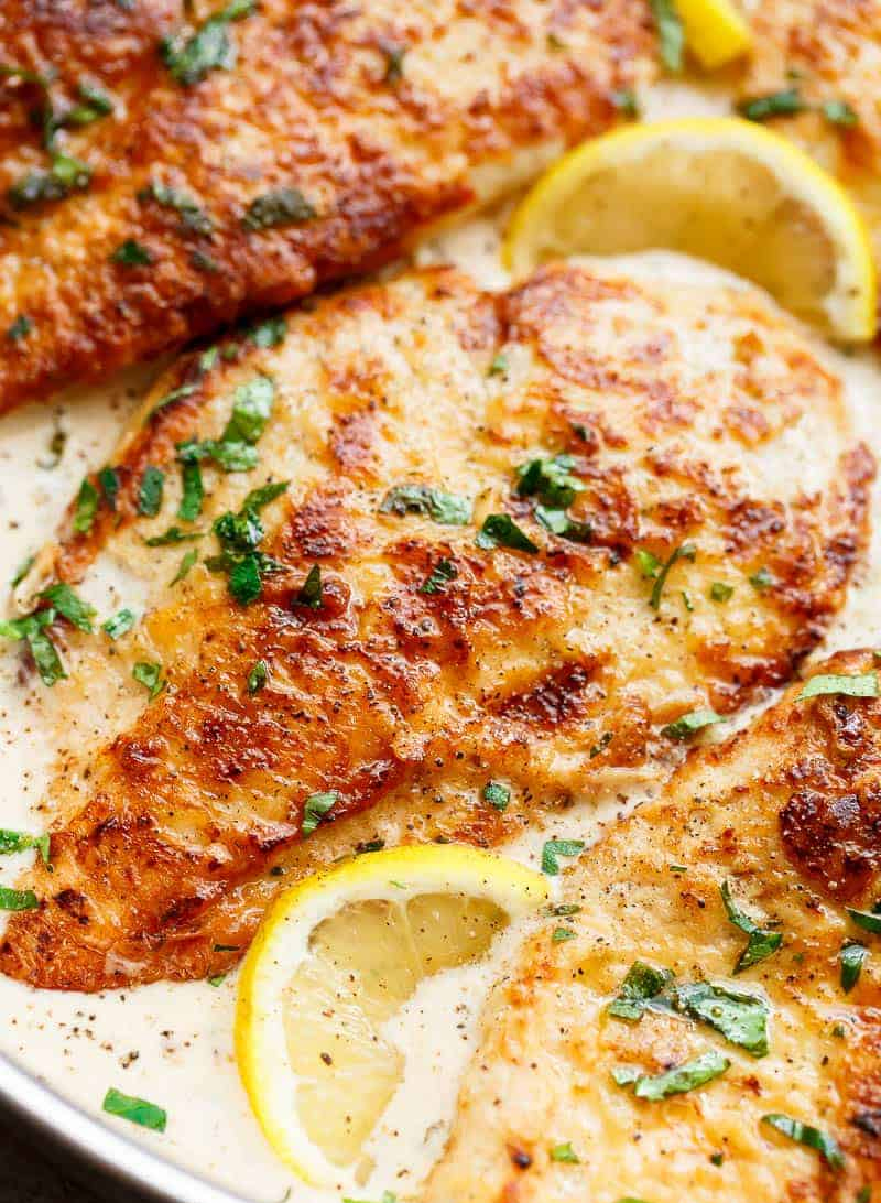 Close-up of a golden-brown, seasoned grilled fish fillet garnished with herbs.