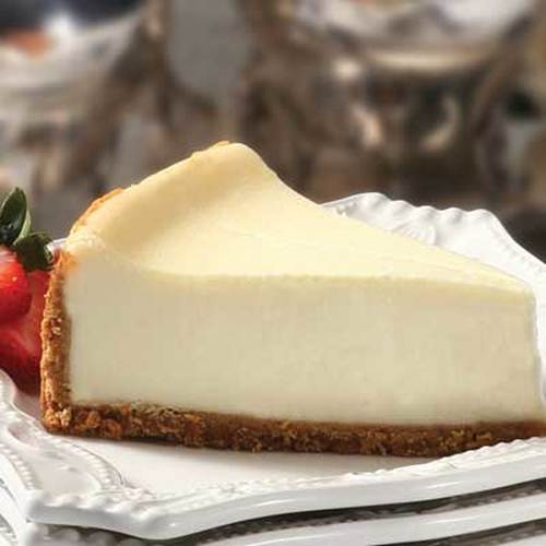 A slice of creamy cheesecake with a graham cracker crust and a strawberry garnish.