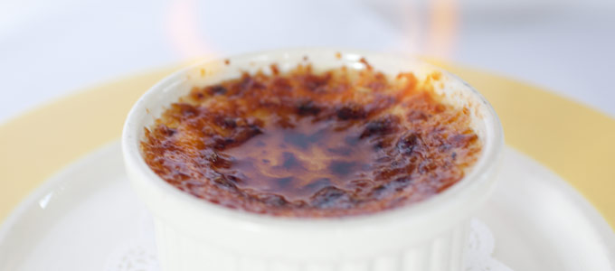 Close-up of a caramelized crème brûlée in a white ramekin.