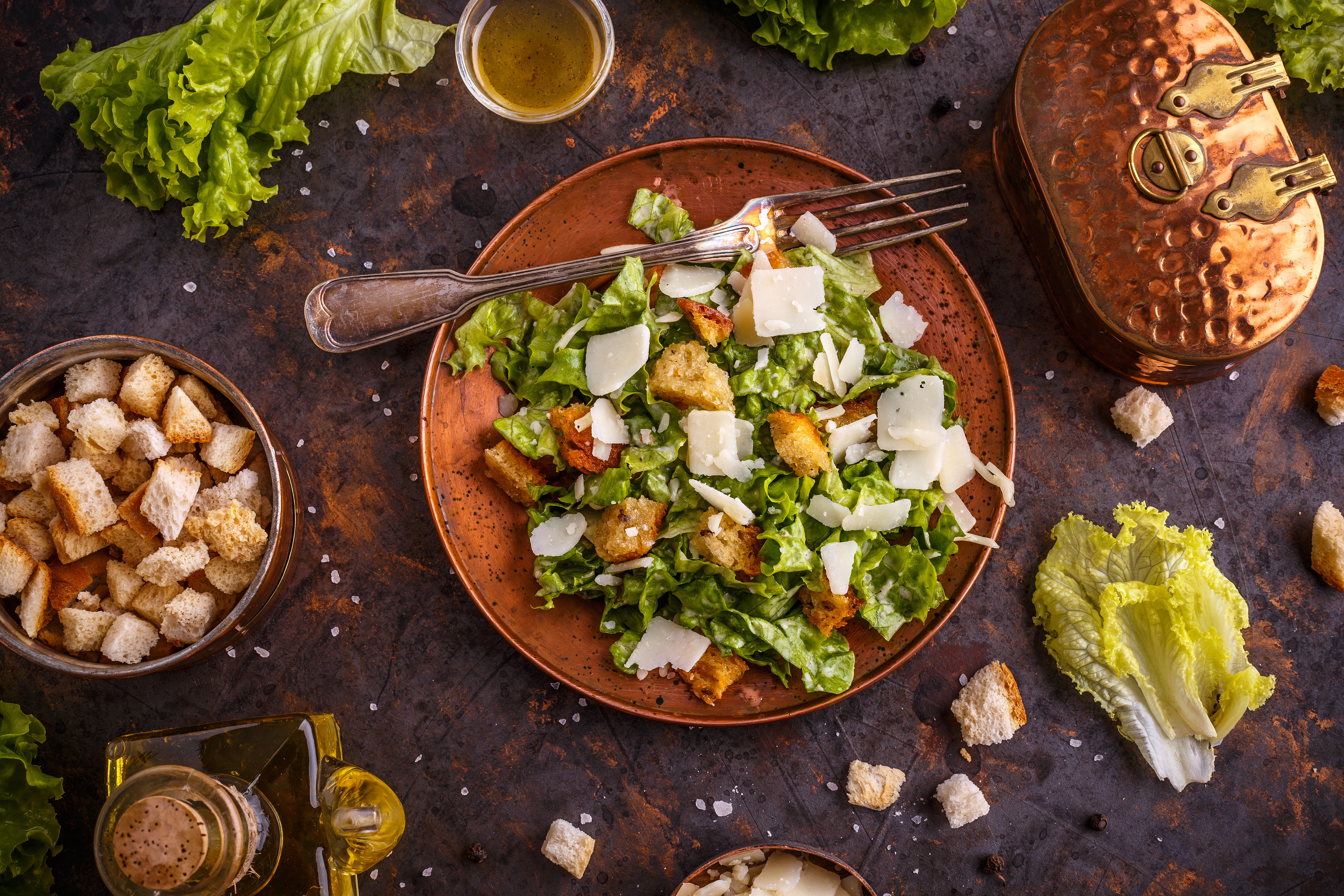 A fresh Caesar salad with lettuce, croutons, and shaved cheese on a rustic plate.
