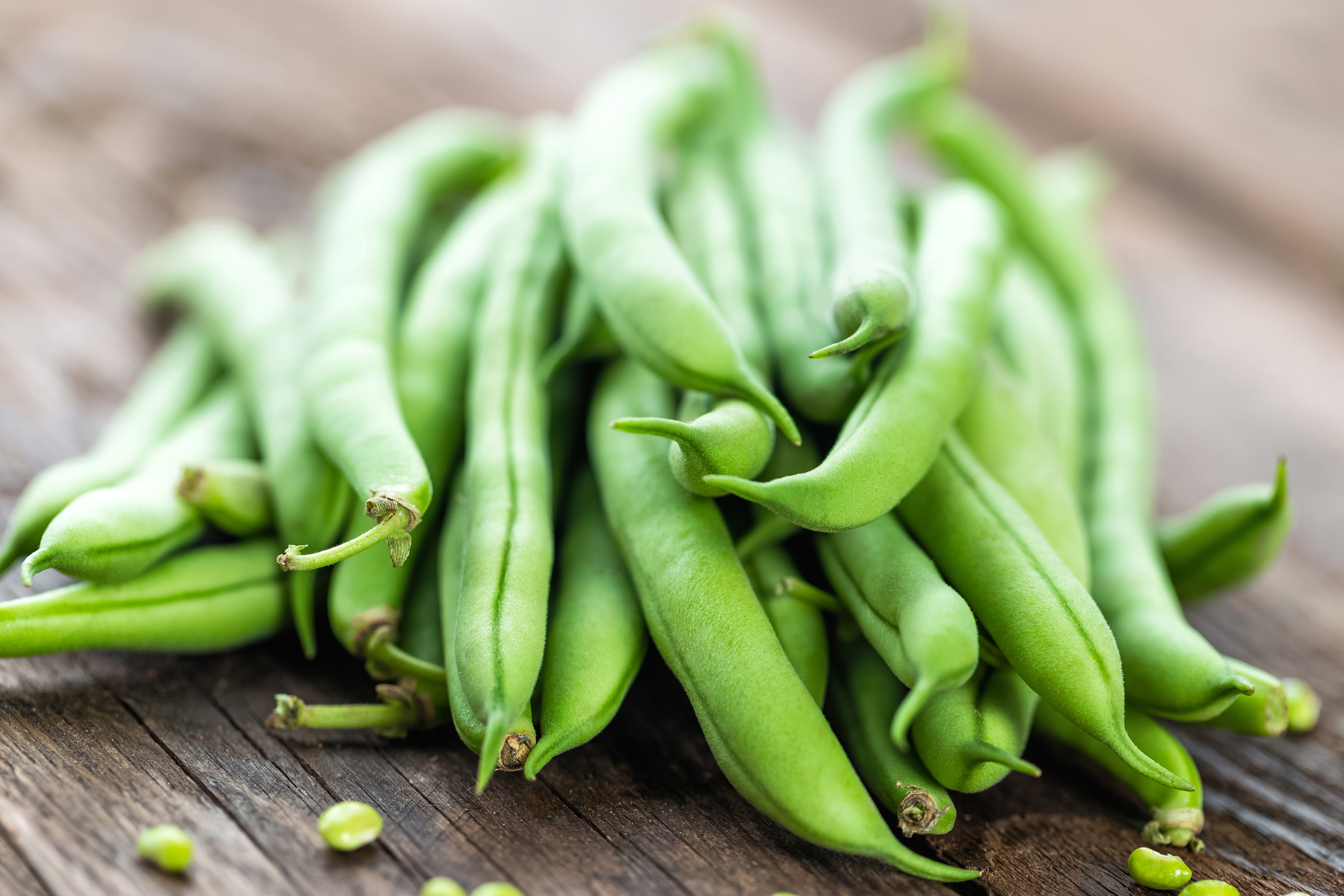 Fresh green beans piled on a rustic wooden surface.