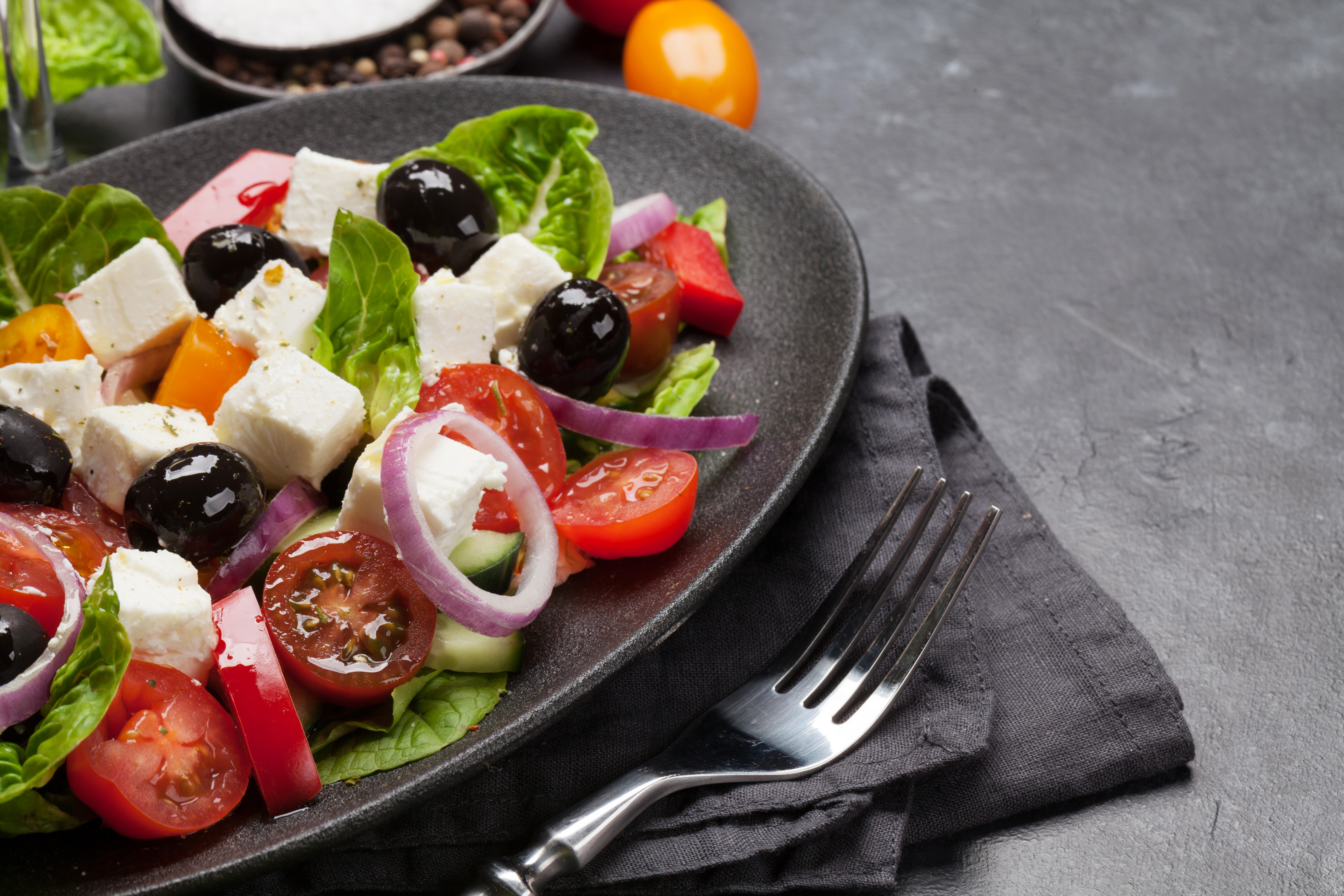 Fresh Greek salad with feta, olives, tomatoes, and onions on a dark plate.