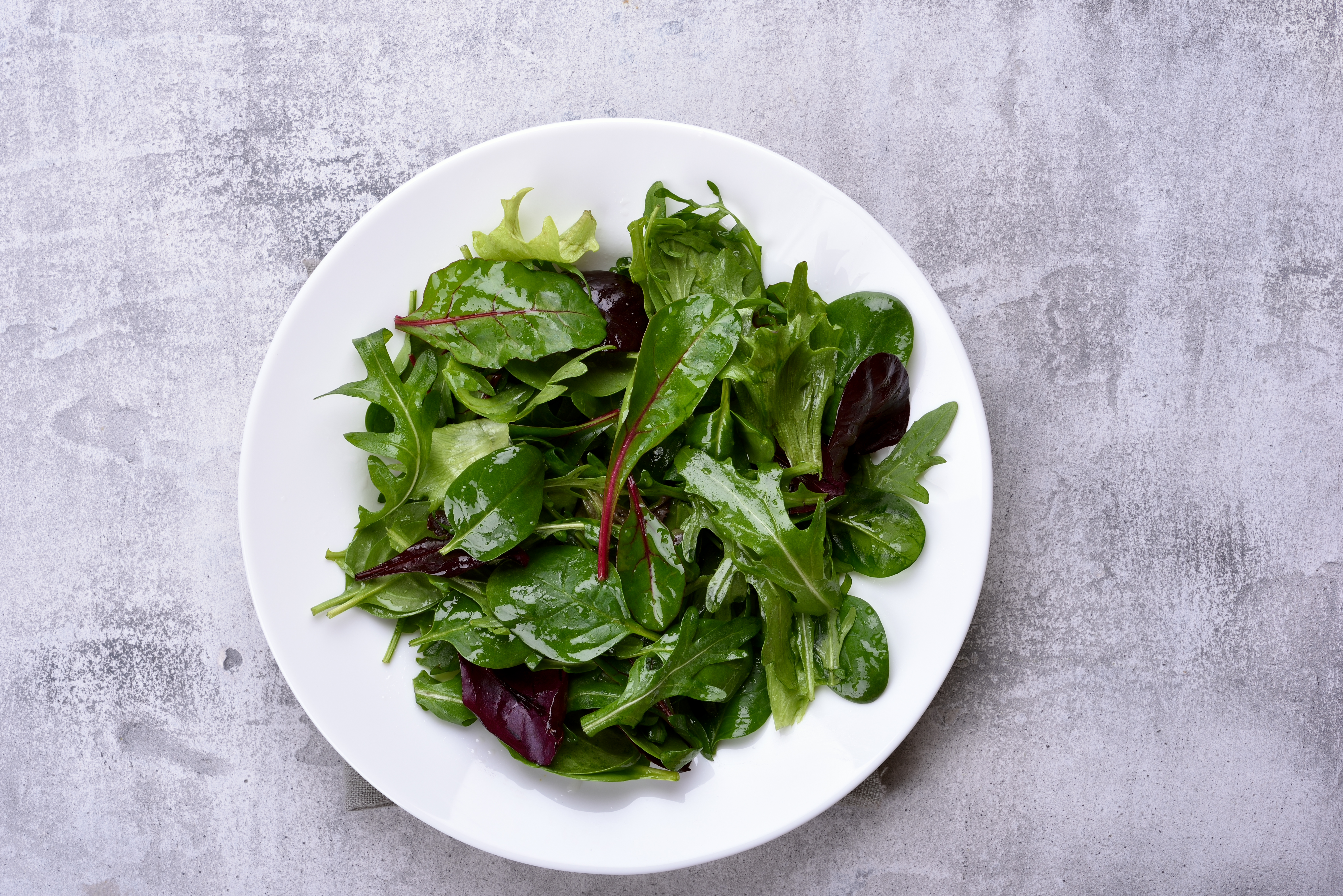 Fresh mixed green salad on a white plate.