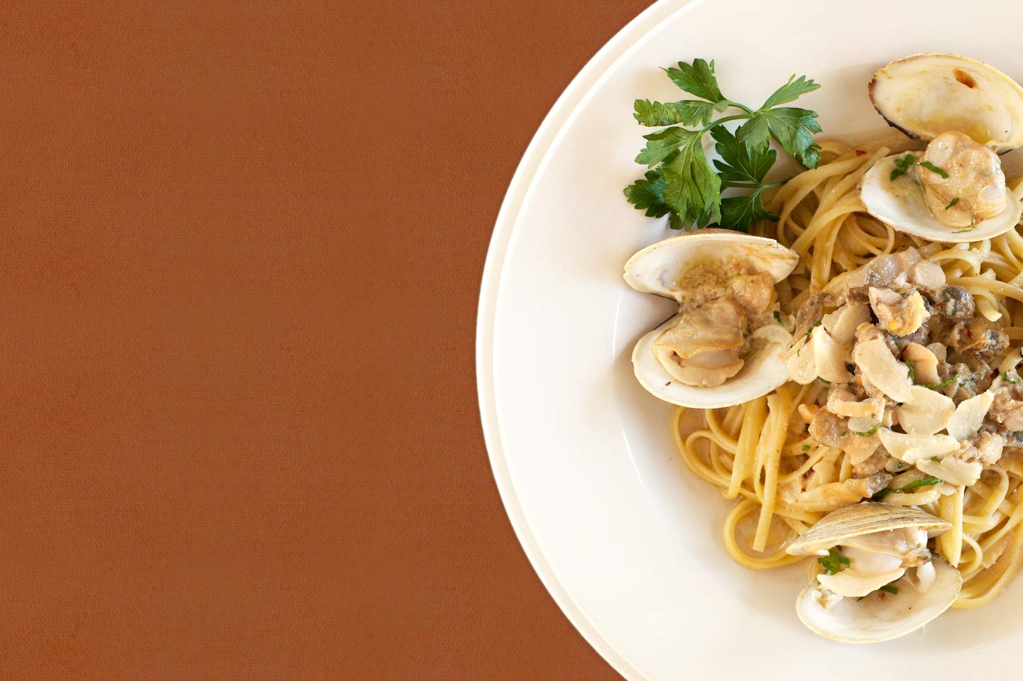 Plate of linguine pasta with clams and parsley on a white dish.
