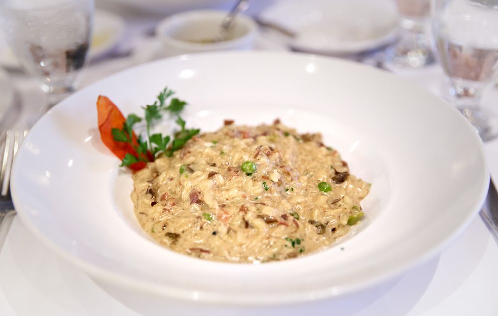 Creamy risotto garnished with herbs and a roasted tomato slice.