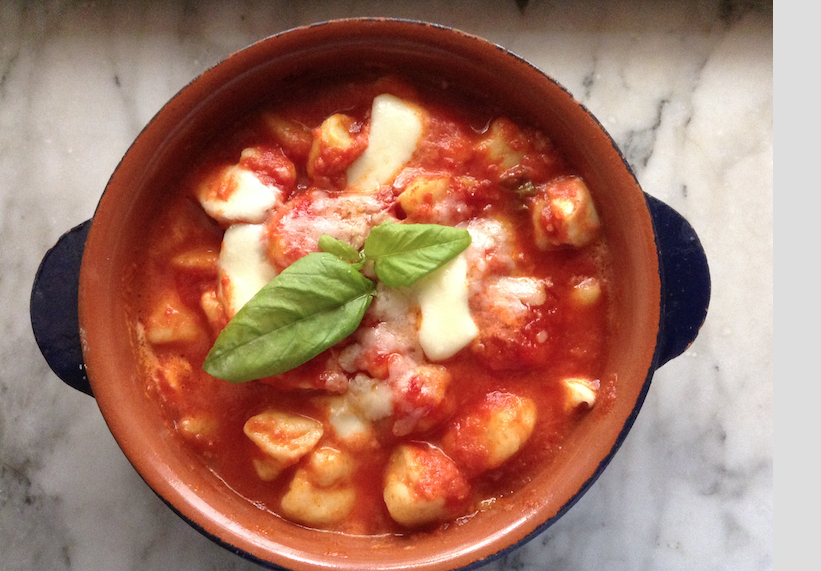 Gnocchi in rich tomato sauce topped with melted cheese and fresh basil.