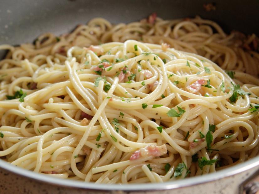 Close-up of spaghetti pasta with herbs and small bits of bacon.