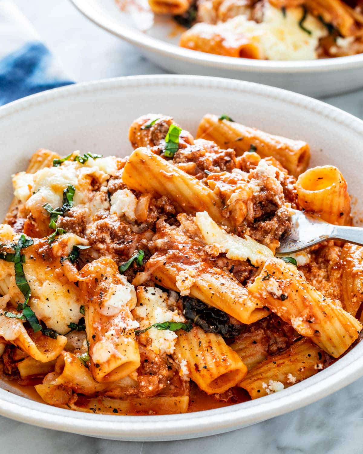 Close-up of rigatoni pasta with meat sauce and melted cheese.