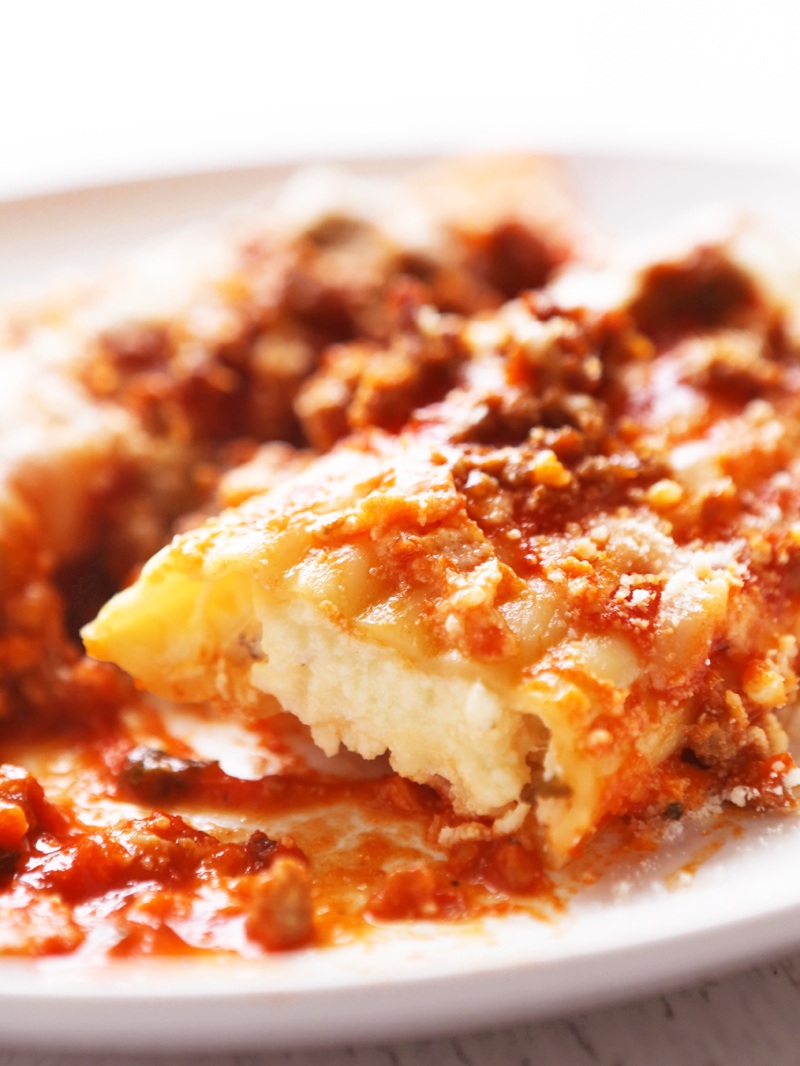 Close-up of a cheesy lasagna slice with meat sauce and melted cheese.