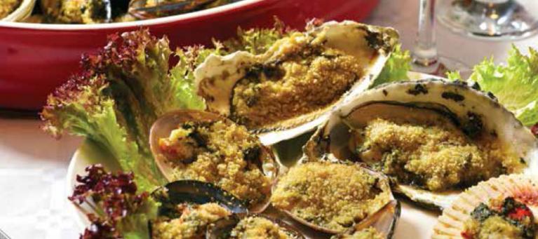 Baked stuffed clams garnished with leafy greens on a plate.