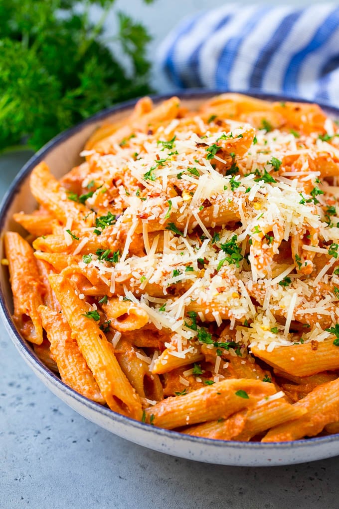 Close-up of penne pasta with tomato sauce, grated cheese, and parsley.