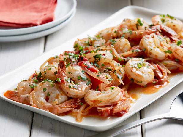 A plate of cooked shrimp garnished with herbs.
