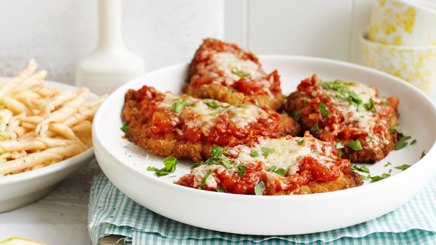Plate of chicken parmesan topped with marinara and cheese.